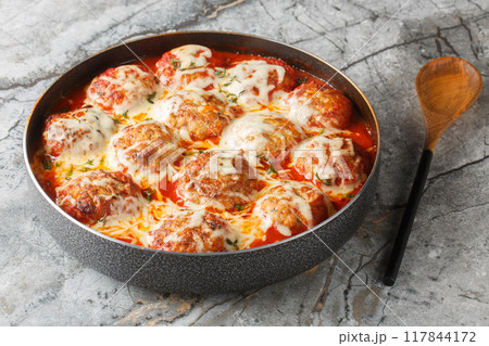 Italian casserole of baked meatballs in spicy tomato sauce with mozzarella cheese and thyme close-up in a baking dish. Horizontal Italian casserole of baked meatballs in spicy tomato sauce with mozzarella cheese and thyme close-up in a baking dish. Horizontal 117844172