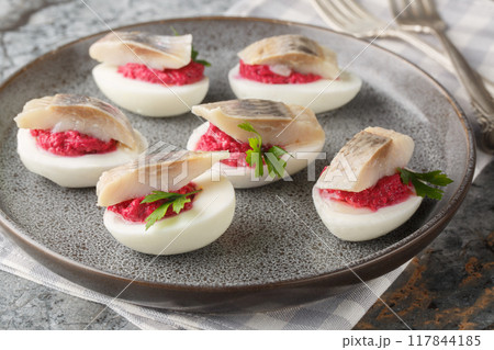 Stuffed eggs with beets and salted fish herring close-up in a plate. Horizontal Stuffed eggs with beets and salted fish herring close-up in a plate. Horizontal 117844185