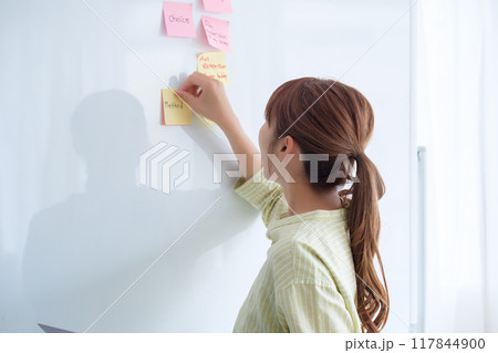 オフィスで課題を見える化する若い女性 117844900