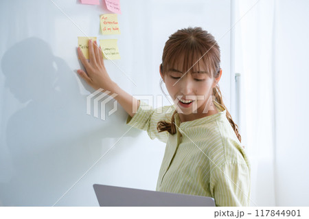 オフィスで課題を見える化する若い女性 117844901