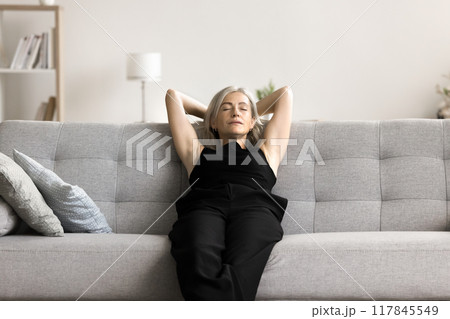 Serene middle-aged woman relaxing leaned on sofa Serene middle-aged woman relaxing leaned on sofa 117845549