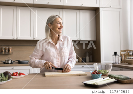 Happy mature 45s chef woman cooking salad at kitchen table Happy mature 45s chef woman cooking salad at kitchen table 117845635
