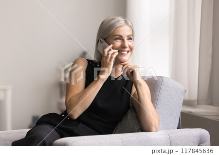 Smiling mature female lead pleasant conversation on smartphone 117845636