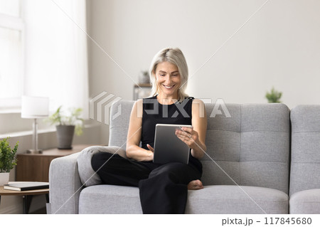Pretty woman sits on sofa explore website using digital tablet Pretty woman sits on sofa explore website using digital tablet 117845680