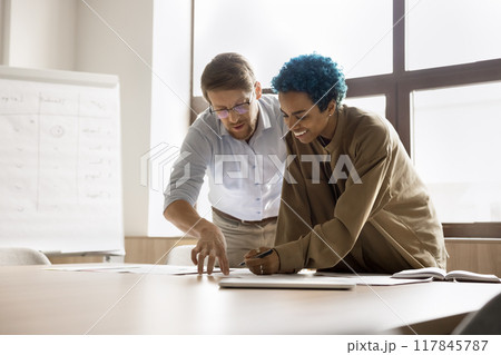 Two colleagues standing at desk, examining printed documents 117845787
