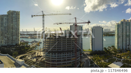 Tower lifting cranes at high residential apartment building construction site. Real estate development in Miami urban area 117846496