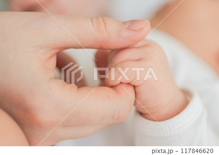 Happy family. Tiny newborn infant baby little hand on mother hand palm. Newborn baby holding parent finger after birth. Mom baby at home. Support protection of new life. Handle with care Happy family. Tiny newborn infant baby little hand on mother hand palm. Newborn baby holding parent finger after birth. Mom baby at home. Support protection of new life. Handle with care 117846620