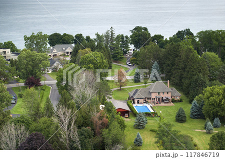 Private residential house in lakeside suburban sprawl area in Rochester, New York. Upscale suburban home with large backyard swimming pool and green grassy lawn in summer season Private residential house in lakeside suburban sprawl area in Rochester, New York. Upscale suburban home with large backyard swimming pool and green grassy lawn in summer season 117846719