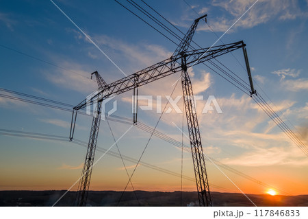 Dark silhouette of high voltage tower with electric power lines at sunrise. Transmission of electric energy concept 117846833