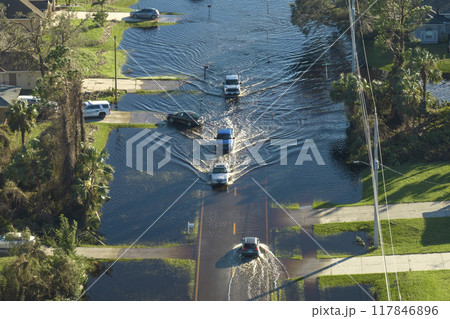 Flooded road in Florida after heavy hurricane rainfall. Aerial view of evacuating cars and surrounded with water houses in suburban residential area 117846896