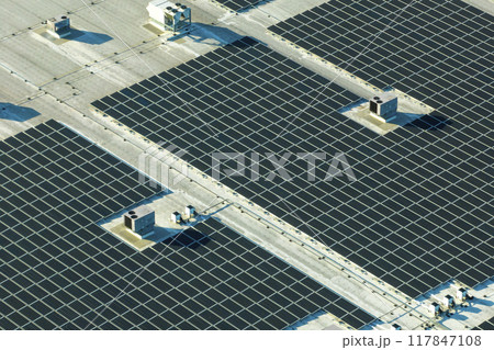 Aerial view of solar power plant with blue photovoltaic panels mounted on industrial building roof for producing green ecological electricity. Production of sustainable energy concept Aerial view of solar power plant with blue photovoltaic panels mounted on industrial building roof for producing green ecological electricity. Production of sustainable energy concept 117847108