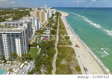 Aerial view of South Beach sandy surface with tourists relaxing on hot Florida sun. Miami Beach city with high luxury hotels and condos. Tourism infrastructure in southern USA Aerial view of South Beach sandy surface with tourists relaxing on hot Florida sun. Miami Beach city with high luxury hotels and condos. Tourism infrastructure in southern USA 117847112