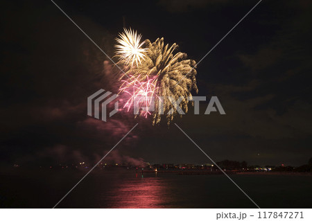 Aerial view of bright fireworks exploding with colorful lights over sea shore on US Independence day holiday Aerial view of bright fireworks exploding with colorful lights over sea shore on US Independence day holiday 117847271