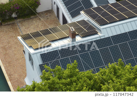 Aerial view of new expensive american building roof with rows of blue solar photovoltaic panels for producing clean ecological electric energy. Renewable electricity with zero emission concept Aerial view of new expensive american building roof with rows of blue solar photovoltaic panels for producing clean ecological electric energy. Renewable electricity with zero emission concept 117847342