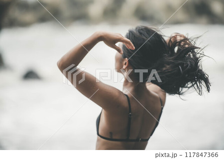 浜辺で髪をまとめる若い女性 117847366