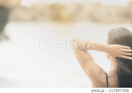 浜辺で髪をまとめる若い女性 117847368
