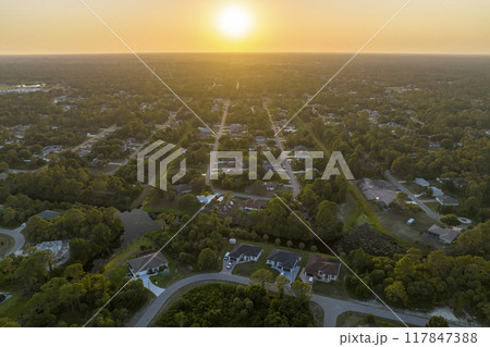 Aerial landscape view of suburban private houses between green palm trees in Florida quiet rural area at sunset Aerial landscape view of suburban private houses between green palm trees in Florida quiet rural area at sunset 117847388