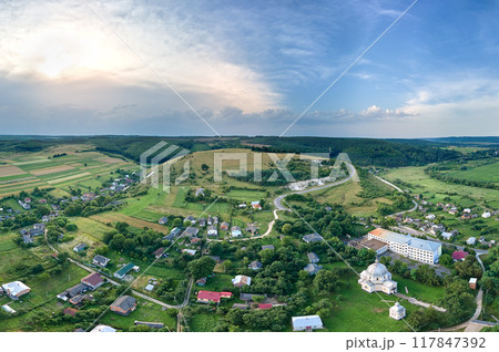 Aerial landscape view of village houses and distant green cultivated agricultural fields with growing crops on bright summer day Aerial landscape view of village houses and distant green cultivated agricultural fields with growing crops on bright summer day 117847392