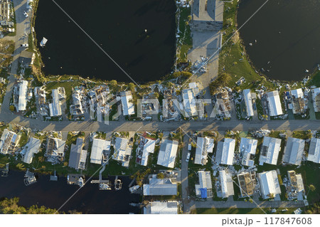 Hurricane strong wind destroyed suburban house roofs in Florida mobile home residential area. Consequences of natural disaster 117847608