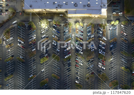Large parking lot with many parked cars. Big carpark at supercenter shopping mall with lines and markings for vehicle places and directions 117847620