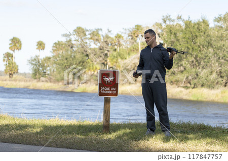 Operator is disappointed because he can not fly his quadcopter in national park no drone area. Man is unable to use his UAV near restriction notice sign 117847757