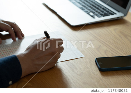 相続税申告書の記入をする男性の手元 117848081