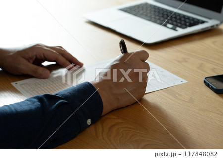 相続税申告書の記入をする男性の手元 117848082