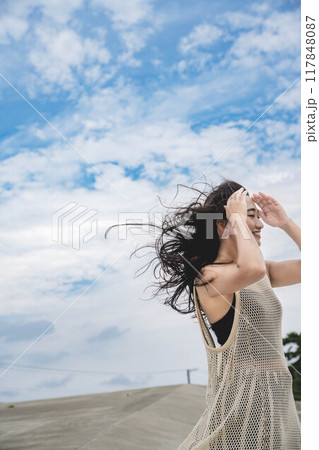 強風の中、海辺で座る女性 117848087