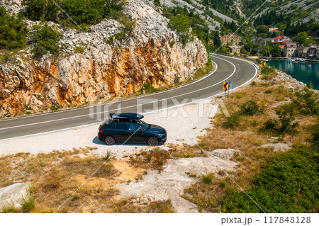 Car with a roof box stands on the side of a cliff and beautiful rocks in the background Car with a roof box stands on the side of a cliff and beautiful rocks in the background 117848128