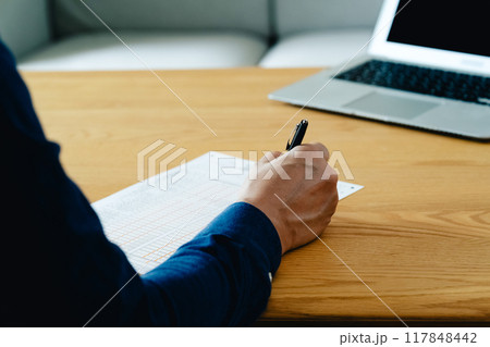 相続税申告書の記入をする男性の手元 117848442