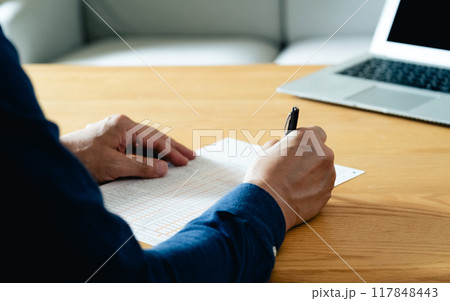 相続税申告書の記入をする男性の手元 117848443