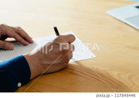 相続税申告書の記入をする男性の手元 117848446