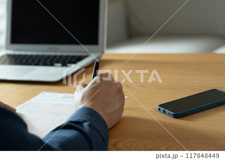 相続税申告書の記入をする男性の手元 117848449