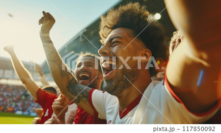 Football fans in stadium cheer wildly, their faces bright with joy as they celebrate thrilling win under afternoon sun. 117850092