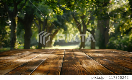 Wooden table surface in front of a blurred forest scene during summer, great for environmental campaigns or nature-inspired marketing. 117850242