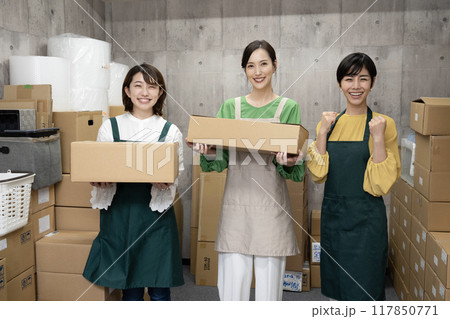 倉庫で段ボール箱を持つ3人の女性社員 倉庫で段ボール箱を持つ3人の女性社員 117850771