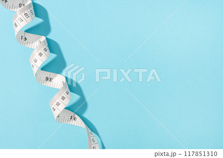 Measuring tape on blue background with copy space. Weight or length concept Measuring tape on blue background with copy space. Weight or length concept 117851310