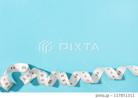 Measuring tape on blue background with copy space. Weight or length concept 117851311