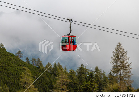 red cable car cabin above the trees on a hill in the fog, Katrin cable car, Bad Ischl, Austria 117851728