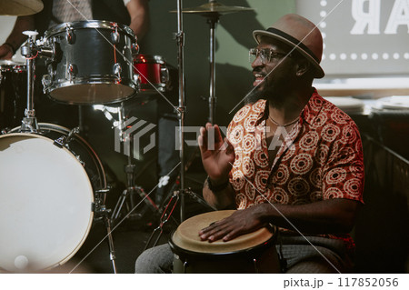 Black Cuban man playing tumbadora and singing during jazz concert in local bar 117852056