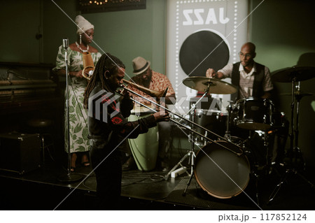 Wide shot of modern jazz band musicians preparing for performance in bar, setting instruments and checking sound 117852124