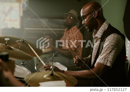 Side view shot of young Black man playing drums in modern jazz music band, copy space 117852127