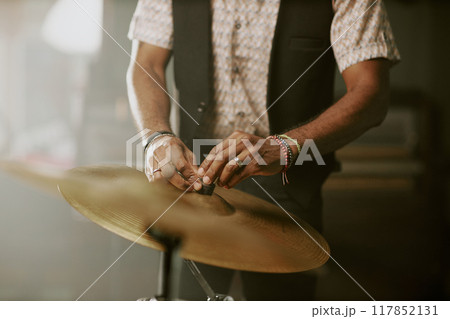 Medium section of unrecognizable musician setting hid drum kit for rehearsal or performance 117852131