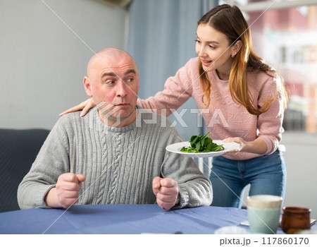 Portrait of a disgruntled man, to whom a young woman brought a plate of spinach Portrait of a disgruntled man, to whom a young woman brought a plate of spinach 117860170