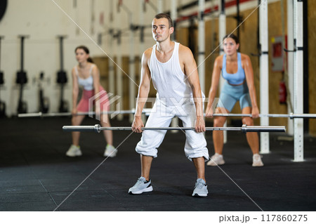 Athletic man doing squats with barbell in gym 117860275