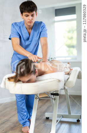 Massage by man in blue scrubs 117860329