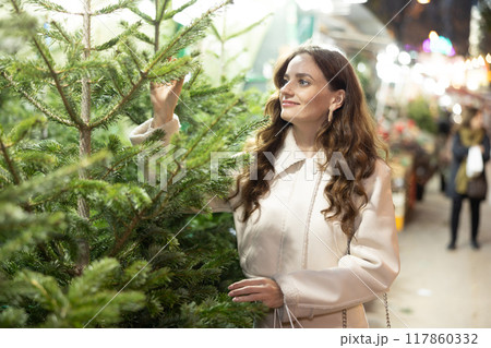 Woman choosing Christmas tree Woman choosing Christmas tree 117860332