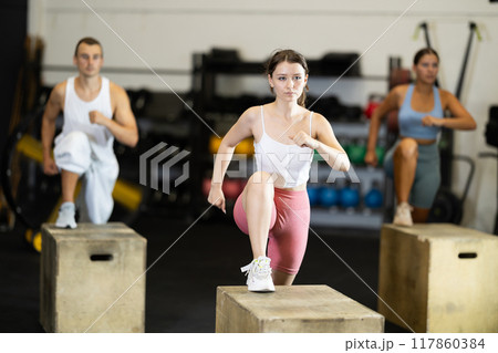 Woman doing muscle stretching. CrossFit in a group with other athletes 117860384