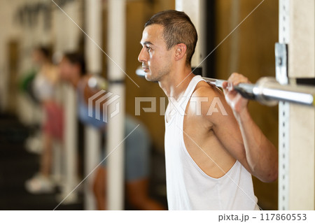Young man lifting barbell in gym 117860553