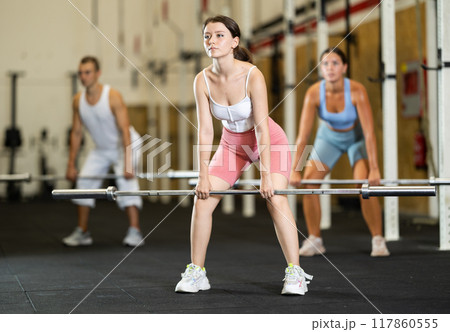 Young woman training with barbell in gym Young woman training with barbell in gym 117860555